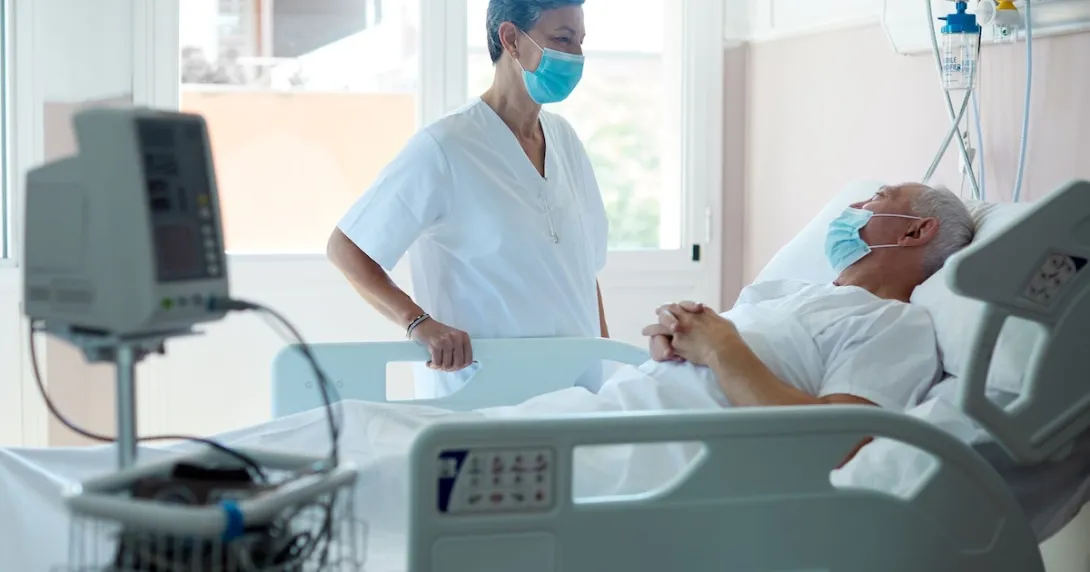 Healthcare provider standing next to a patient in a hospital bed