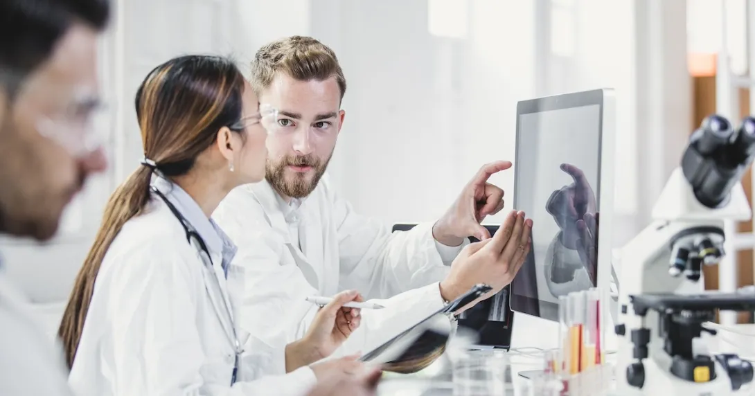 Three healthcare providers standing around a computer looking at the screen