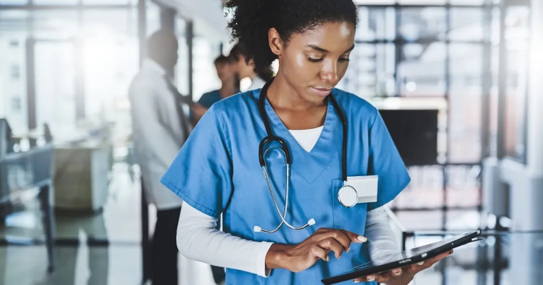Healthcare professional in scrubs looking at a tablet