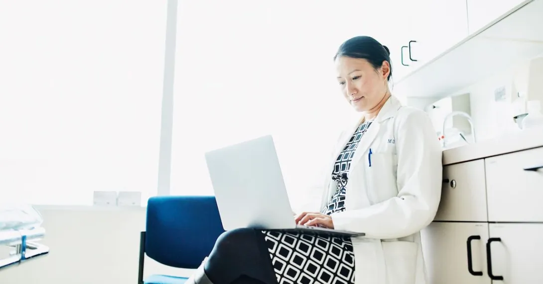 A doctor answering online inquiries on a laptop