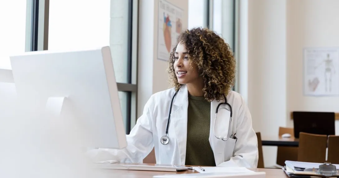 A doctor reviewing a patient record on a desktop computer