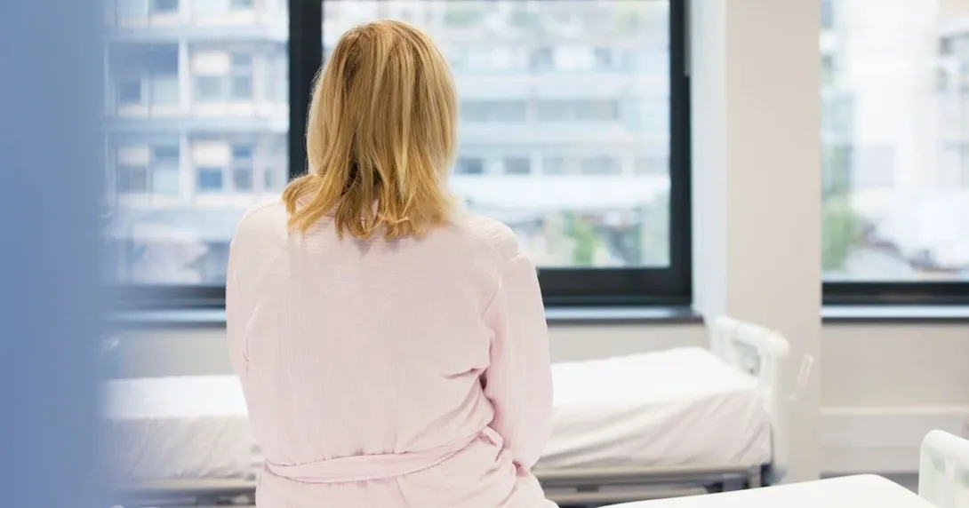 A woman sitting with her back to the camera on a hospital bed