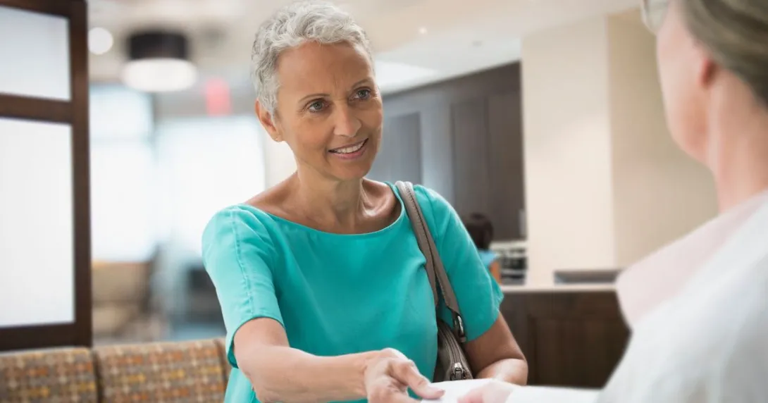 A woman handing her insurance card to a provider